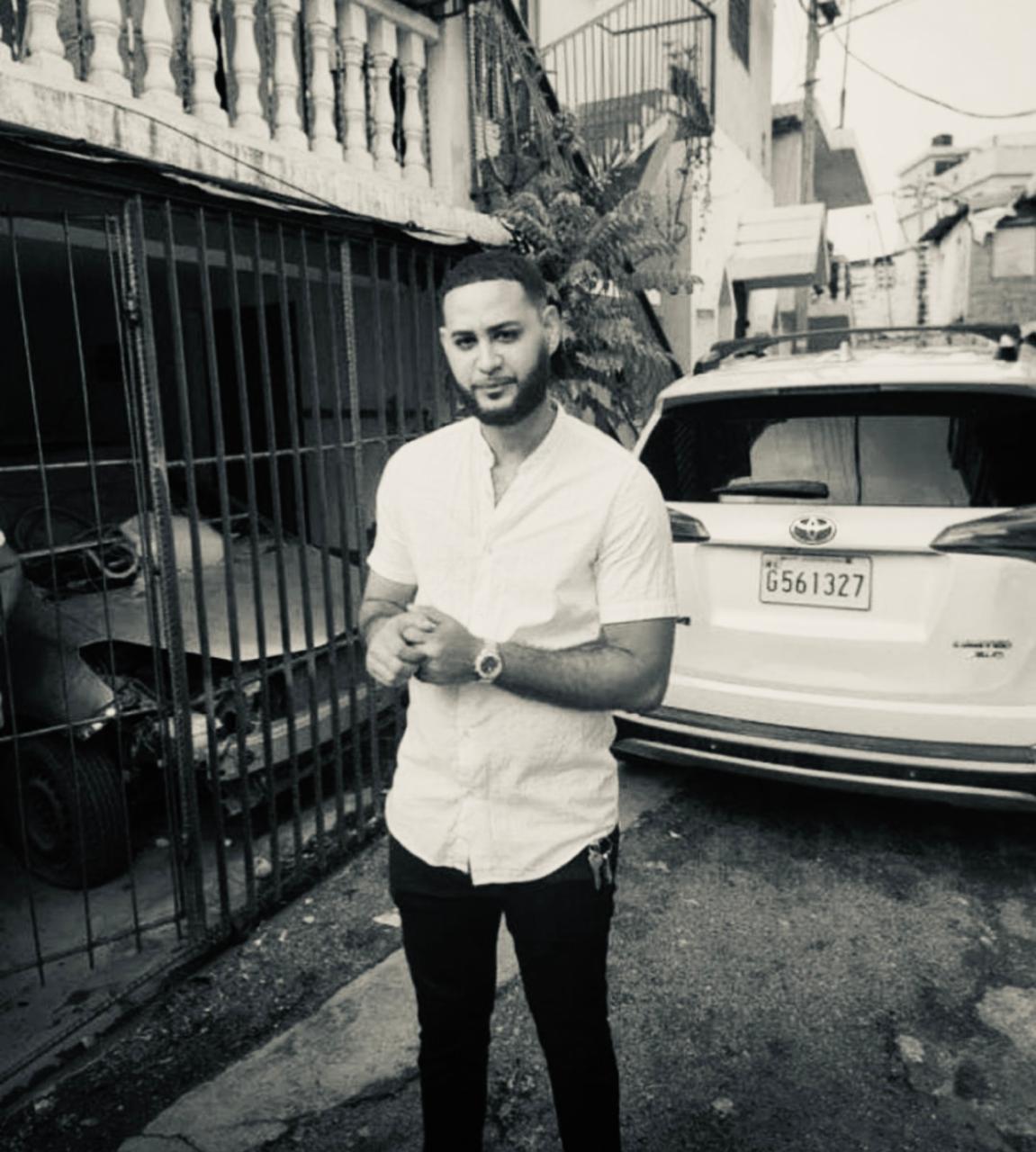 Hombre de pie junto a coche estacionado.