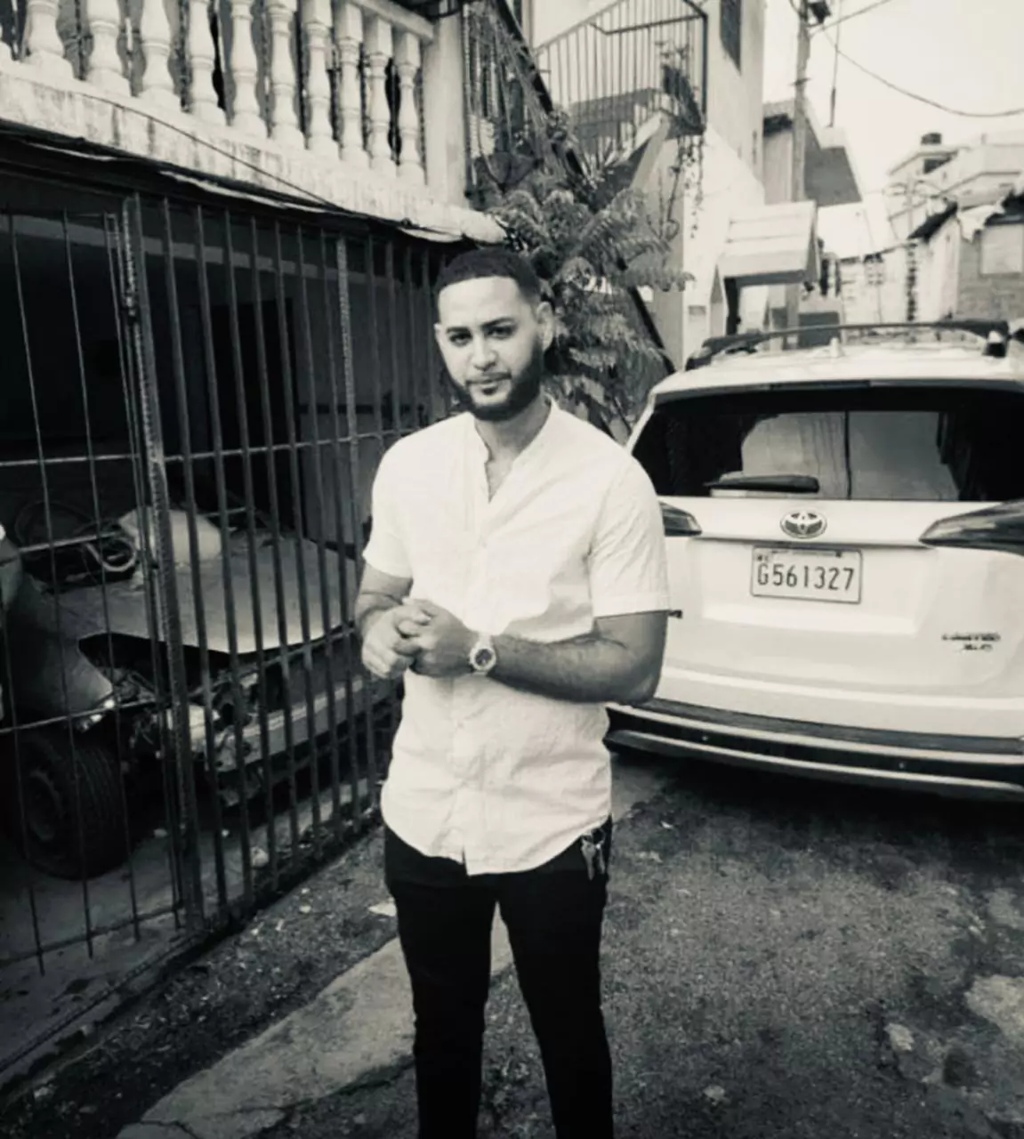 Hombre de pie junto a coche estacionado.