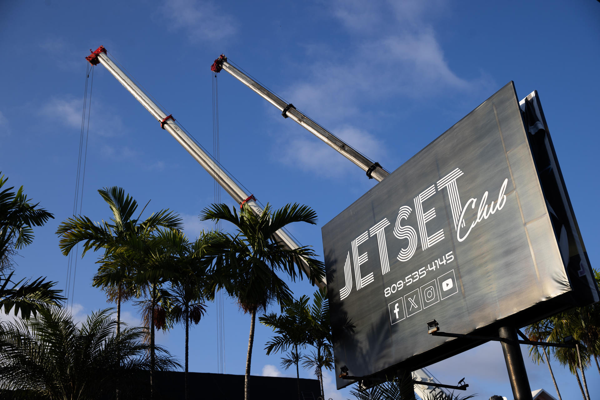 Cartel de discoteca entre palmeras y grúas