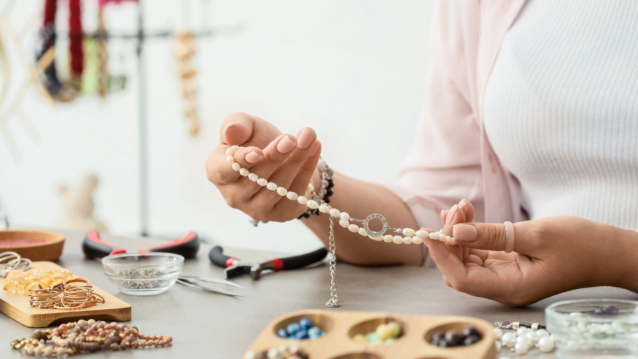 Persona haciendo joyas artesanales con cuentas y herramientas.