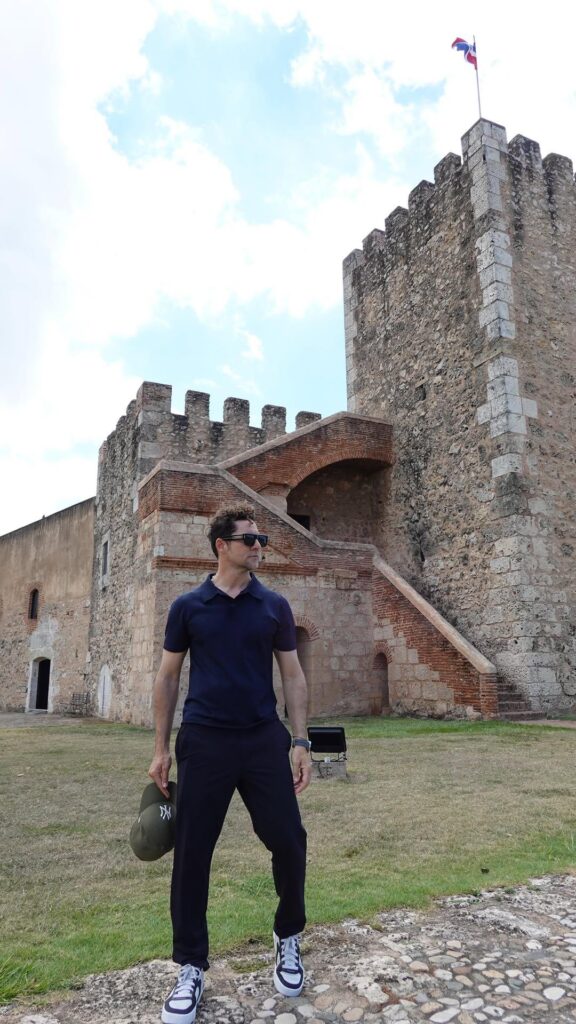 Hombre frente a una torre medieval con bandera ondeando.
