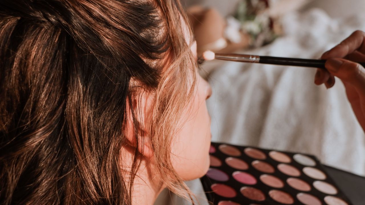 Mujer aplicándose sombra de ojos con pincel