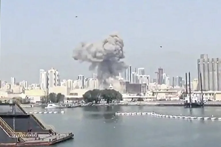 Columna de humo tras una explosión en una zona urbana vista desde la costa