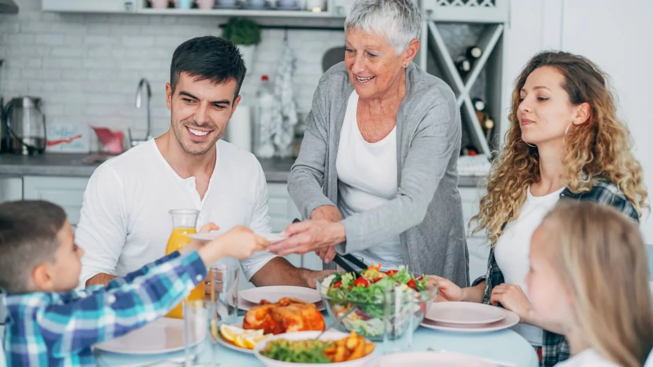 Familia comparte un almuerzo con ensalada y pollo, asociado a recomendaciones para comer antes de media tarde